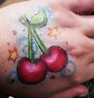 A pair of cherries on my hand made entirely of eye shadows and makeup medium