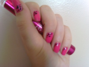 Bright pink nail, with black hearts and dots 