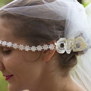 Chapel length 1920s style bridal cap. Wavy hair reminiscent of a Marcel, pinned up in a low bun. Natural skin-look and vibrant pink lip.