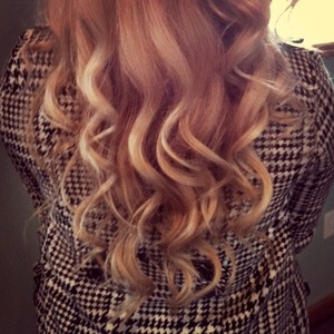 Blonde hair curled with a wand. 