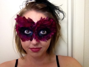 A mask made out of fuchsia feathers attached to the skin with eyelash adhesive.