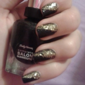 Black nail polish with gold glitter diagonaly across.