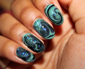 This was a winteryish swirl water marble design. x)
In my opinion, it came out a bit muddy looking, but I still loved it.
I used Sinful Colors Open Seas & Sally Hansen Black Out for the water marble. And the blue flakies on top were L'oreal The Holographic.