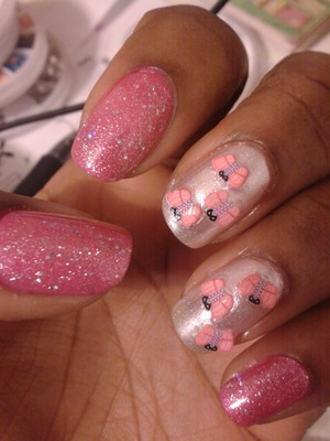 Pink nail polish with pink glitter over it and a sparkly white polish with butterfly fimos 