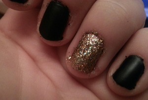 black natte nails with a gold sparkly ringfinger. 