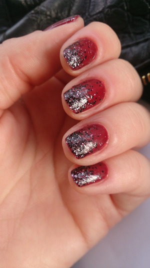 Dark red nail polish sprinkled with silver/black glitter.