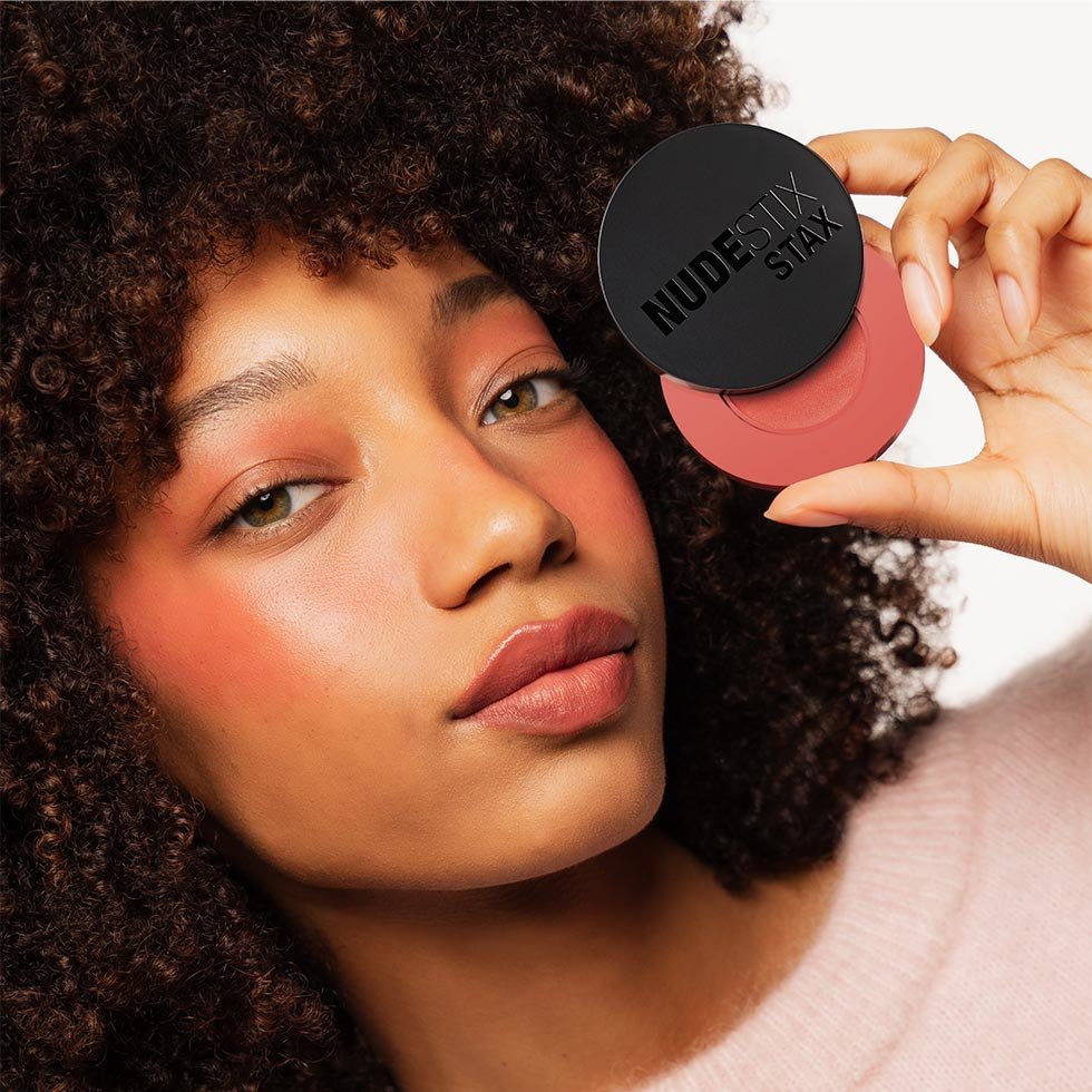 Nudestix model wearing the Stax All Over Color Blush Balm in Cheeky Coral