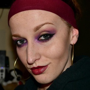 purple and gold shadows, with bold liner and deep red lip.
