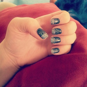 Silver glitter fading on black polished nails.