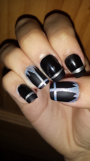 Black matte nails with metallic crosses on thumb and ring finger. Rest are shiny black base tipped with matte black and a metallic stripe.