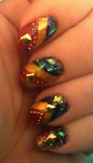 deep purple,red, and gold nails decorated with snow like flakes,gold beads, and gold square studs.