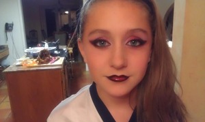 My little cousin wanted me to do her makeup. I said, "What color?" 
"Red and black!"
"Dramatic or normal?"
"Dramatic!"

So yeah. She has hard to work with eyelids, so I had to cut her crease in a way I'm not used to. Aaaand, that's it! I used shadows from a huge e.l.f. pallet, and Nyx's Jumbo Eyeshadow Pencil in Milk. For the lips, I mixed eyeshadow (sounds icky, but it works and I'm a teen on a budget), and clear lipgloss (vanilla mint flavored, from Bath and Body Works). And then drugstore foundation/pressed powder. She's such a sweetie. 