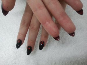 Black nails with red bottoms, and a teardrop gem.