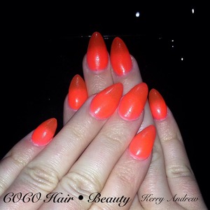 Sculptured acrylic nails polished in a neon orange 