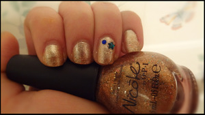 The base is a glittery gold, with a bronze/sequined gradient toward the tips (as seen in the bottle).