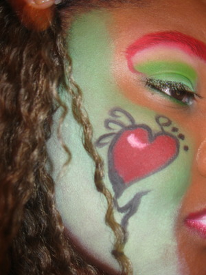 This is my first cheek painting. I choose a heart! I added a red eyebrow with a green eye and eyelashes. 