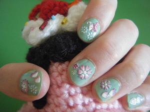Two coats of IsaDora Vintage Mint nail polish, some 3D nail stickers on that, and a coat of clear nail polish on top.