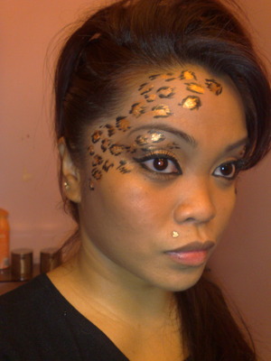 Basic bronzed shadow on lid with winged liner. Cheetah spots along eye, temple, and forehead