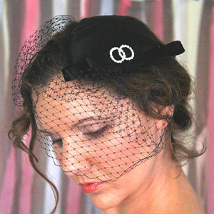 Juicy lips and a sultry eye under 1950s style black organza cocktail hat.
