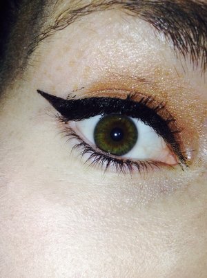 Green eye with a brown shadow and a dark black liner 