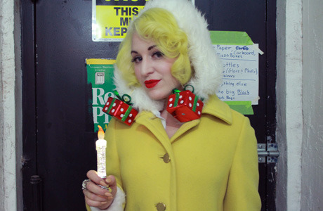 Mischa is looking pin-up perfect in Lime Crime Velveteen lipstick, warm yellow curls, and garishly giftable earrings.