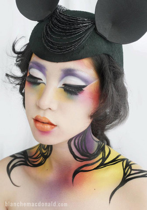 Makeup by Blanche Macdonald Makeup student Catlyn Jeong.

“With this look, I wanted to create something funky something that is totally different and vibrant yet still matching with my previous work. To create a more fantasy look on the face, I airbrushed vibrant colors using Golden Airbrush Paint in purple, yellow, green red and blue. I applied false lashes top and bottom to intensify the look. As for the bottom lashes, I placed about them approximately 5mm away from the natural lashes. I was inspired by the necklace which I placed on the hat and therefore, extended the pattern by created a similar, flowy pattern into the neck.”