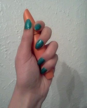 short rounded stiletto nails with green nail polish and blue glitter