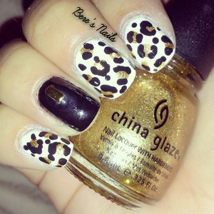 Black and white base nails with a gold and black leopard print and a solid black accent nail with a rectangular gold stud.