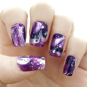 I made these outer space inspired nails using the water marbling technique with 3 colours (dark purple, bright purple and a holographic silver) 
I embellished with 2mm rhinestones of the same colour variety and then finished with a coat of clear silver glitter polish.
Hope you like!
GFx