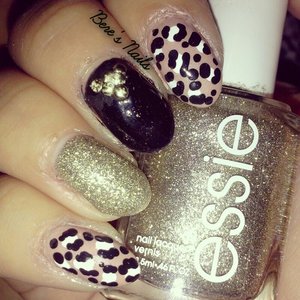 A simple black and white leopard print design over a beige base. With black and gold accent nails and round gold studs.