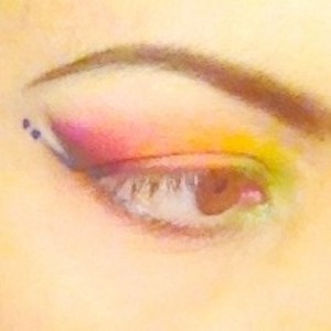 Inspiration: Bird of Paradise. Seven shadow colors (from inner to outer corner: lime green, taxi yellow, bold orange, warm red, Barney purple, light sparkly pink - under lashes- and gold-flecked ivory - on brow bone. Three liner colors (white - to line inner rim and as a highlight between the two other liner wings-, top wing lined from corner of eye outwards with a sparkly emerald green pencil and lower wing lined from corner of eye outwards with electric blue liquid. Two electric blue dots follow the tip of the lower wing. Lashes are bare. 