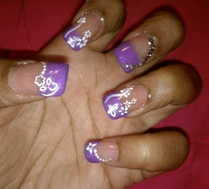  Purple with white flowers and rhinestones on accent nail. 